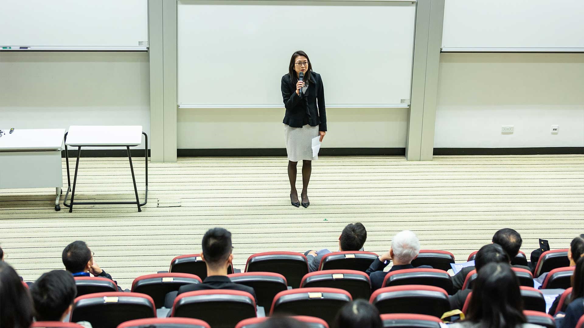 A staff member delivering a presentation to a lecture hall of students